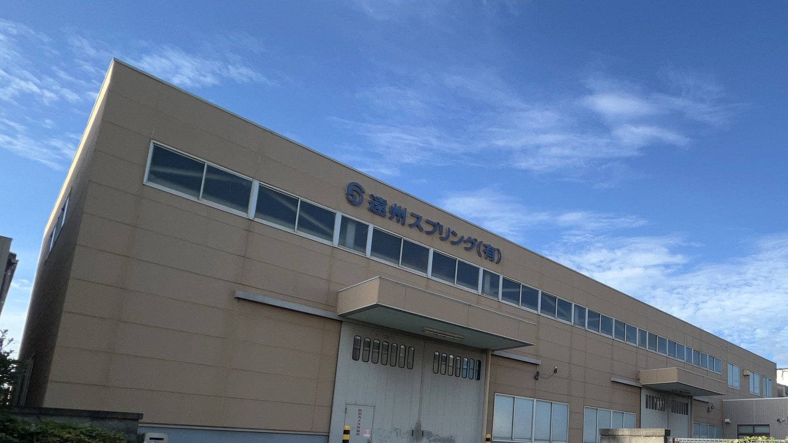 遠州スプリング有限会社の工場外観。壁面に社名の看板が掲げられている
