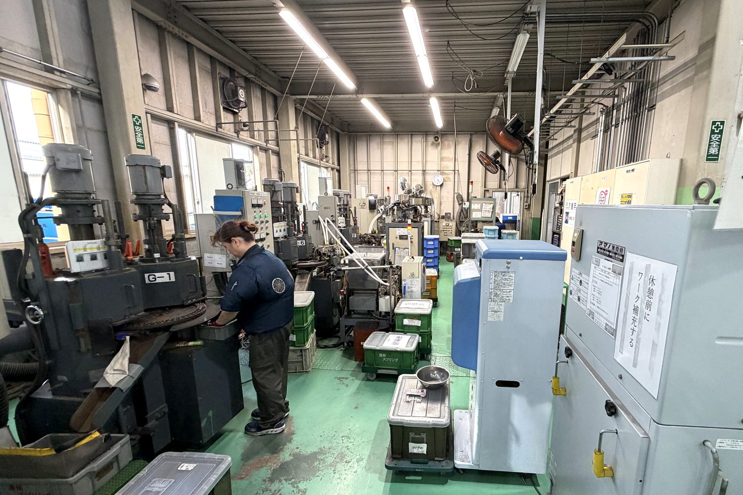 研磨機が並ぶ工程。作業者が研磨機の前でバネを扱っている