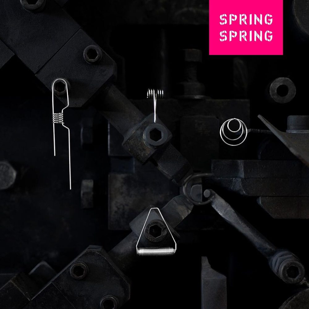 黒い機械部品を背景に、バネでつくったアクセサリーが並ぶSPRING SPRINGのイメージ写真